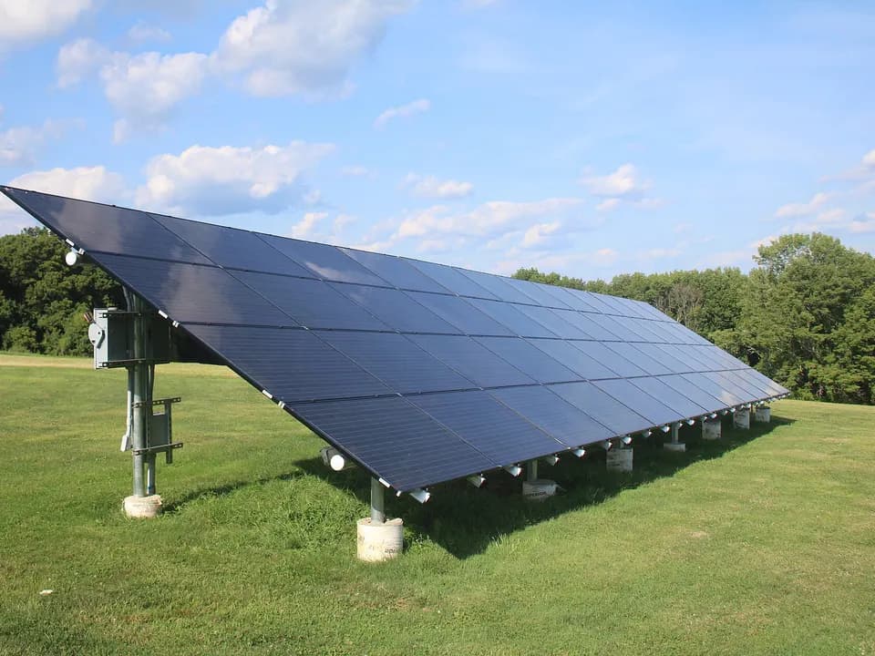 Une rangée de grands panneaux sur un support au sol, dans un champ